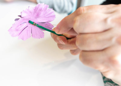 hand tying wire to stem of flower button